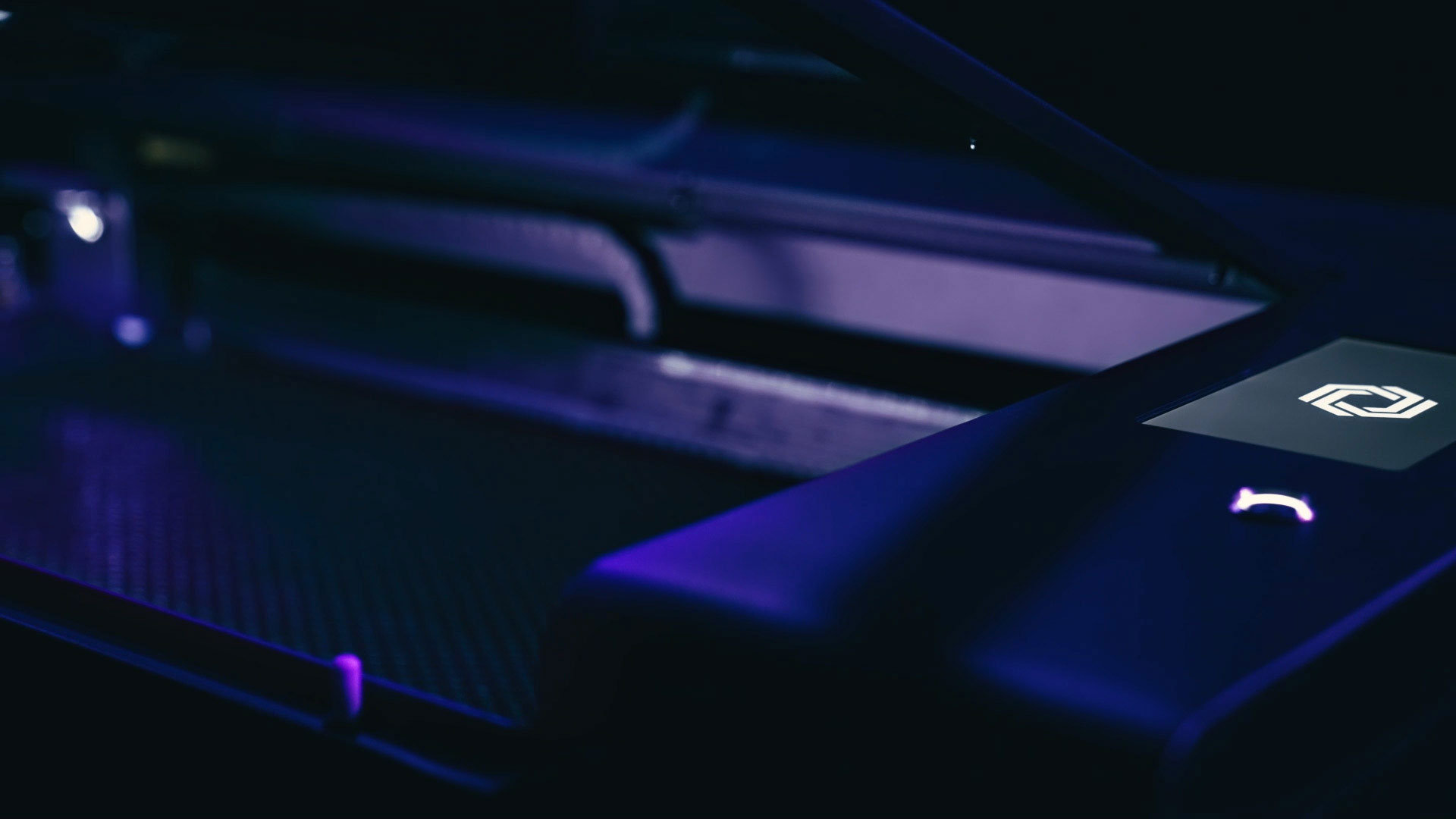 Blue and purple lighting cast over a closeup of a HEXA Laser Cutter